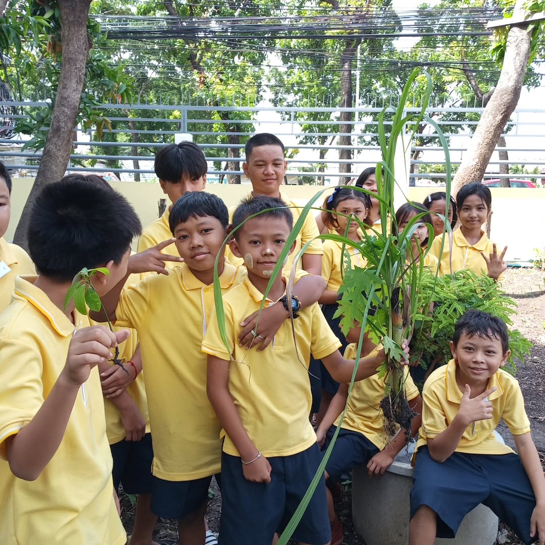 Kong Lah School students holding plants during an outdoor activity.