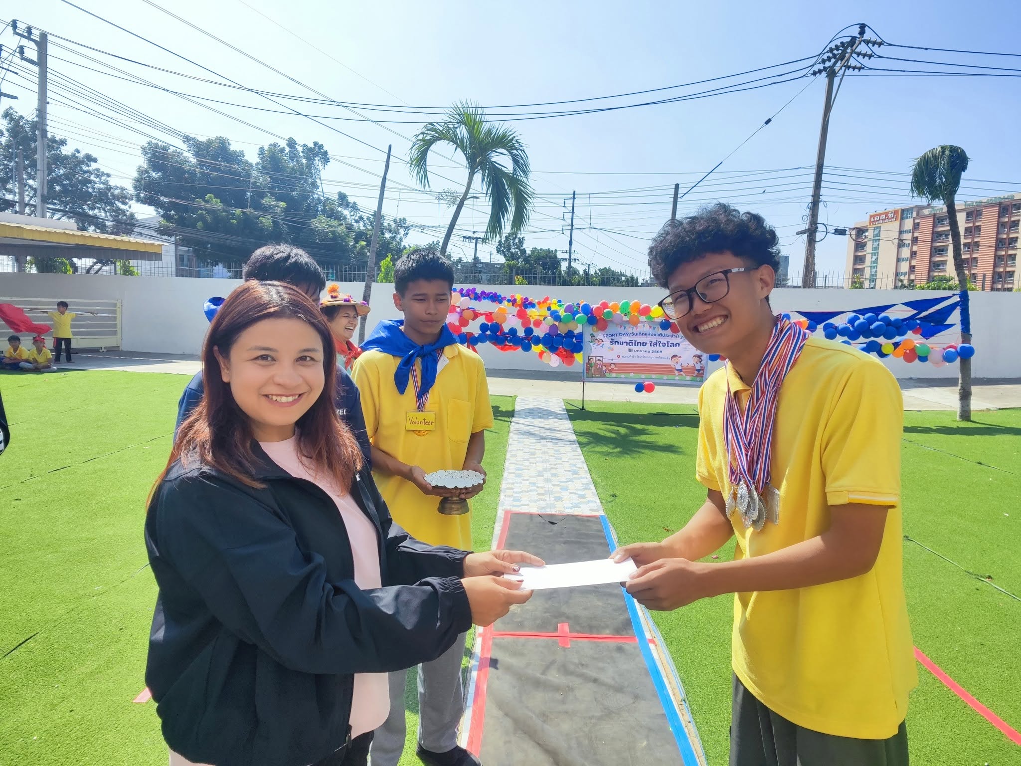 Kong Lah School student receiving recognition during an outdoor school event.